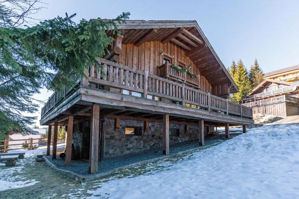 Balkón pod štítom s vianočnou girlandou, pod ním terasa na stĺpoch.